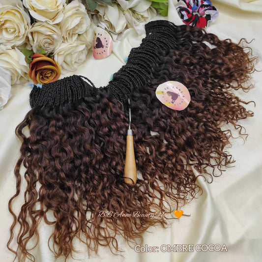 Ombre cocoa hair extensions with a crochet hook on a white fabric background with flowers.
