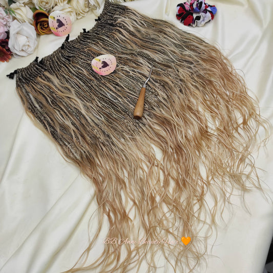 Brown and blonde ombre hair extension with a comb on a white surface, surrounded by flowers.