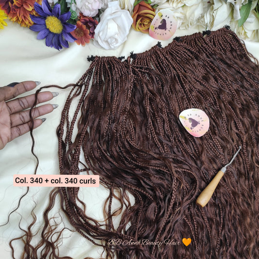Brown braided hair extensions with a crochet hook on a white surface with flowers.