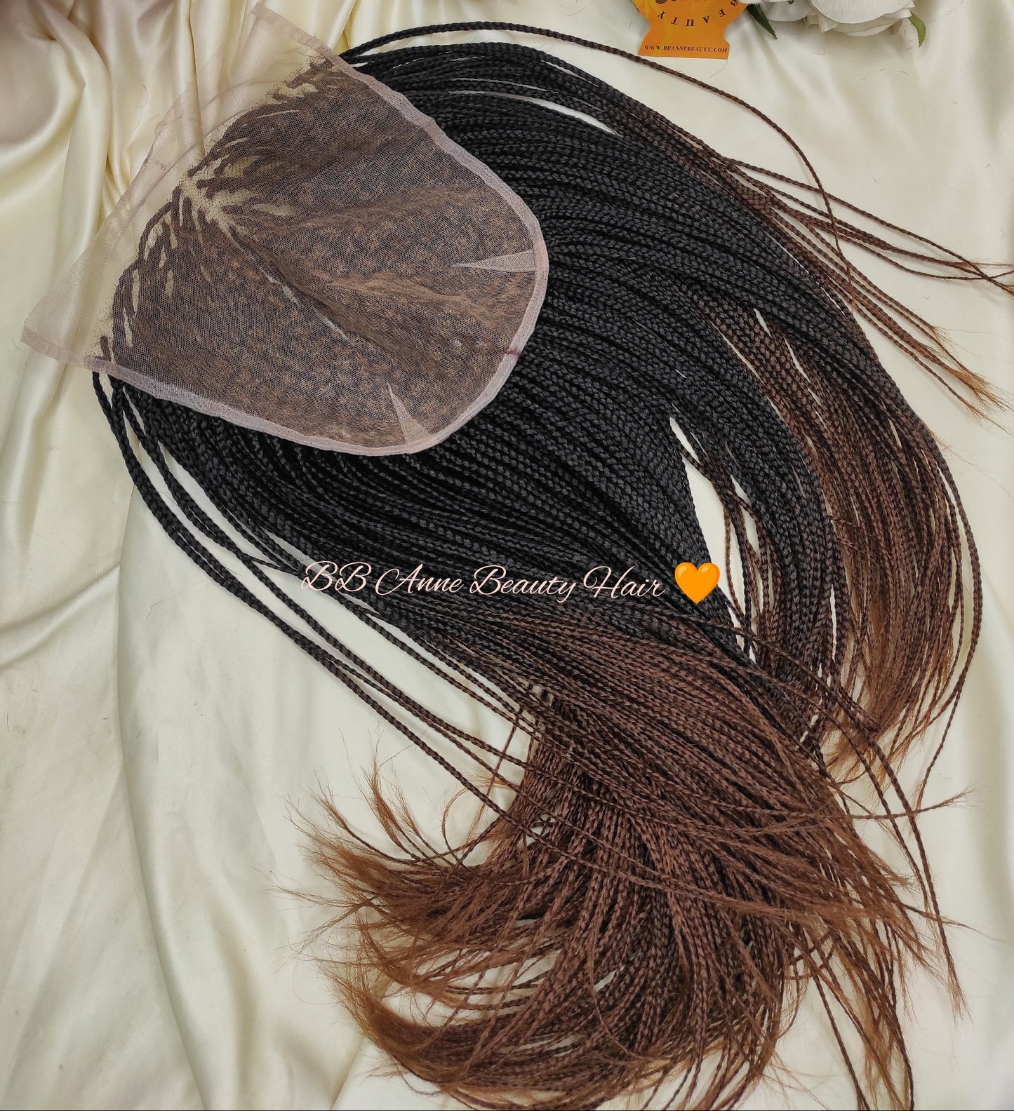 Brown hair extensions with a lace closure on a white surface with flowers and a box.