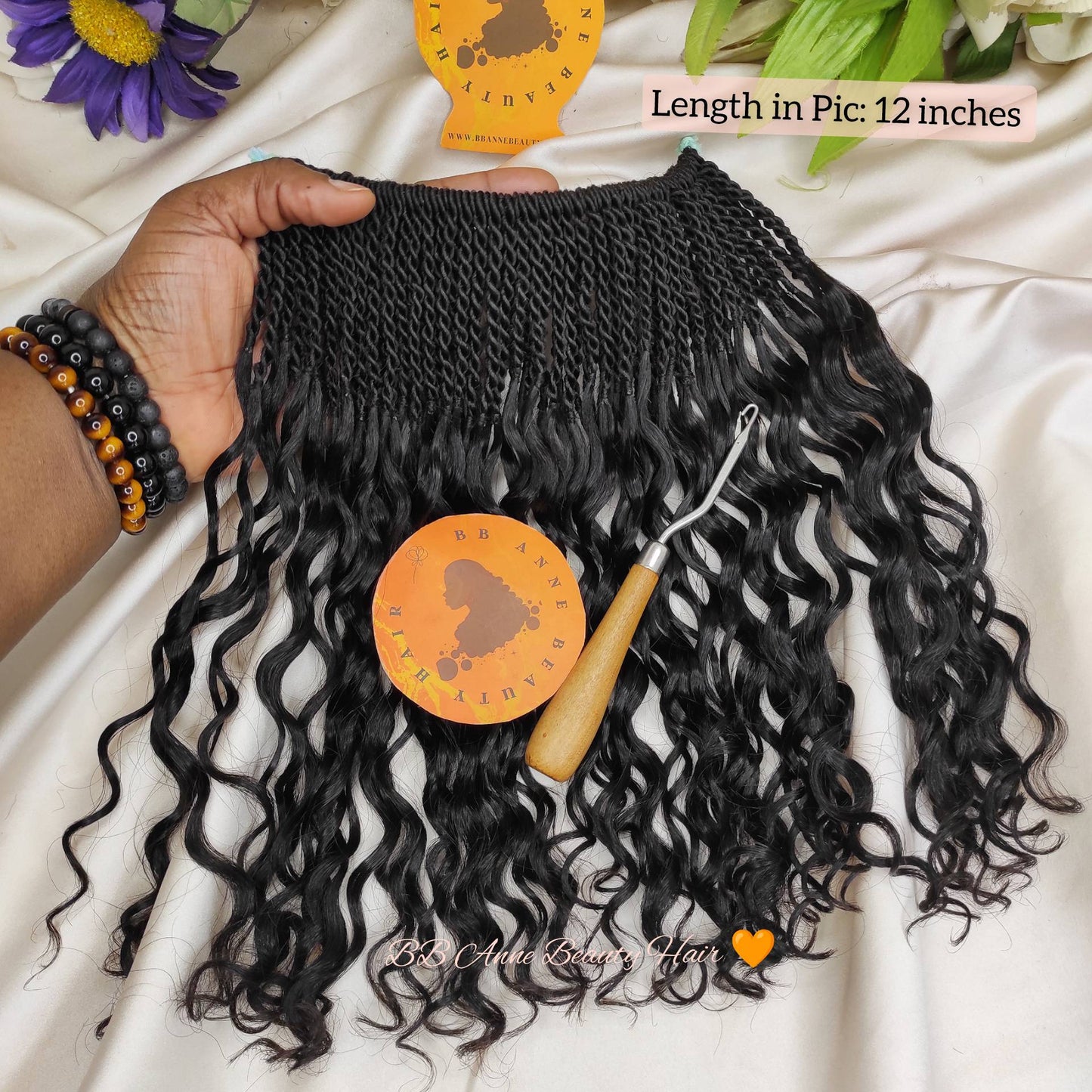 Black braided human hair extensions with a crochet hook on a white fabric background, featuring  bb anne beauty brand logo.
