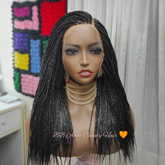 Mannequin head with a black braided wig in front of a colorful quilt.