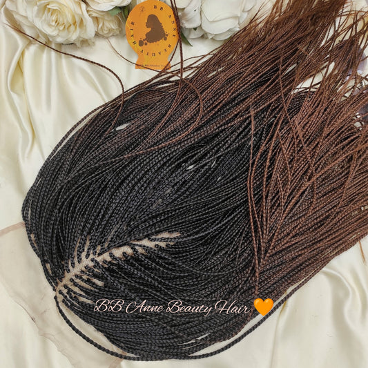 Black and brown braided hair extensions with decorative feathers on a white fabric background.
