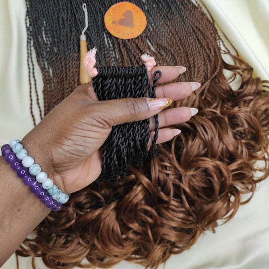 Hand holding black crochet french curl twists with a crochet hook, surrounded by brown hair extensions on a white background.